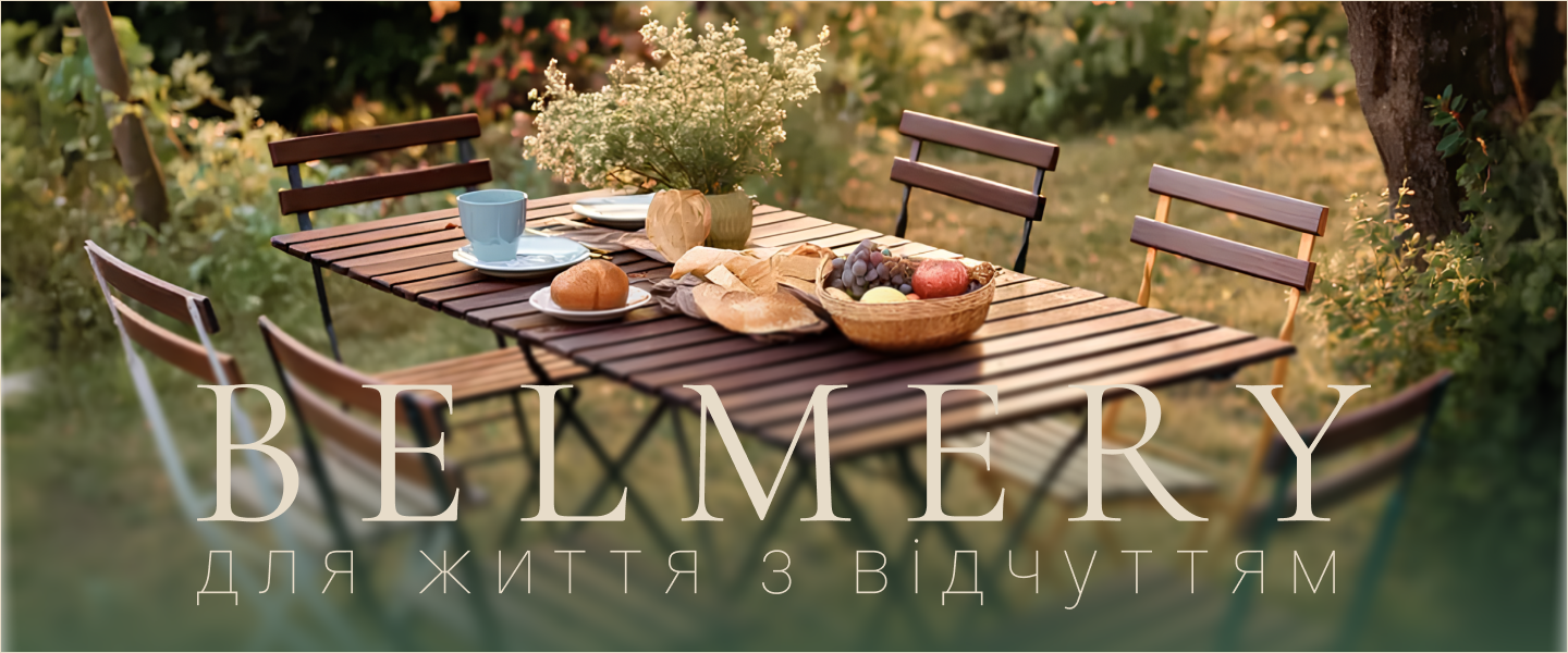 Меблі Belmery на терасі серед зелені — стіл із хлібом, фруктами та квітами, атмосфера затишку просто неба.